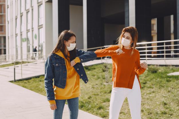 Two women walking along side each other wearing COVID masks